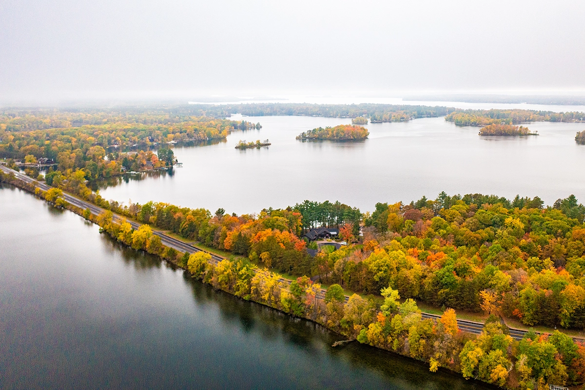 Photo-of-a-road-with-a-lake-on-both-sides-on-a-misty-fall-day-surrounded-by-forest.webp